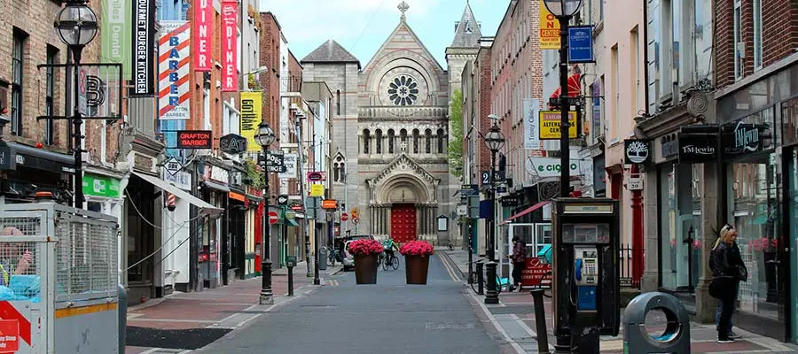 Calle de una ciudad de Irlanda con el fondo de una catedral.